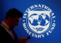 FILE PHOTO: A participant stands near a logo of IMF at the International Monetary Fund - World Bank Annual Meeting 2018 in Nusa Dua, Bali, Indonesia, October 12, 2018. REUTERS/Johannes P. Christo/File Photo