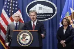 FBI Director Christopher Wray, center, flanked by Attorney General Merrick Garland, left, and Deputy Attorney General Lisa Monaco, speaks to reporters as they announce charges against two men suspected of being Chinese intelligence officers for attempting to obstruct a U.S. criminal investigation and prosecution of Chinese tech giant Huawei, at the Department of Justice in Washington, Monday, Oct. 23, 2022. (AP Photo/J. Scott Applewhite)