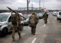 TOPSHOT - Ukrainian servicemen carry rocket-propelled grenades and sniper rifles as they walk towards the city of Irpin, northwest of Kyiv, on March 13, 2022. - Russian forces advance ever closer to the capital from the north, west and northeast. Russian strikes also destroy an airport in the town of Vasylkiv, south of Kyiv. A US journalist was shot dead and another wounded in Irpin, a frontline northwest suburb of Kyiv, medics and witnesses told AFP. (Photo by Dimitar DILKOFF / AFP)