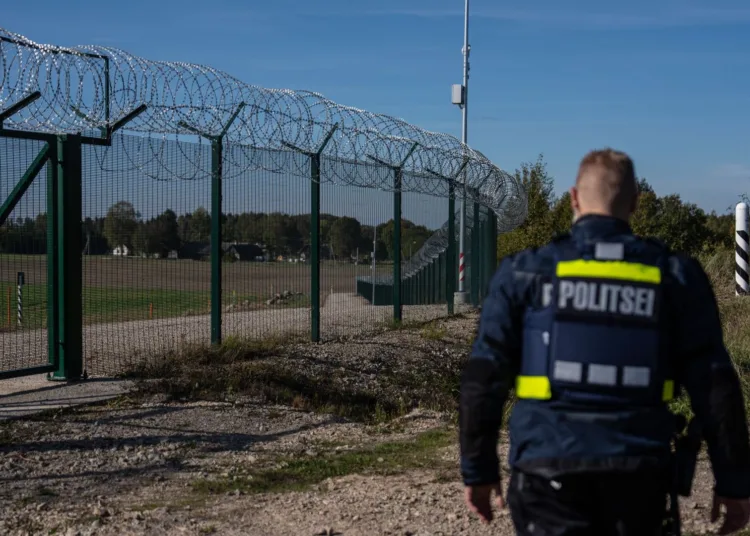 Un agente de la policía fronteriza estonia vuelve a entrar por una puerta de una valla de seguridad que marca la frontera entre Estonia y Rusia en Vinski, Estonia, el 1 de octubre de 2025. (Carl Court / Getty Images)