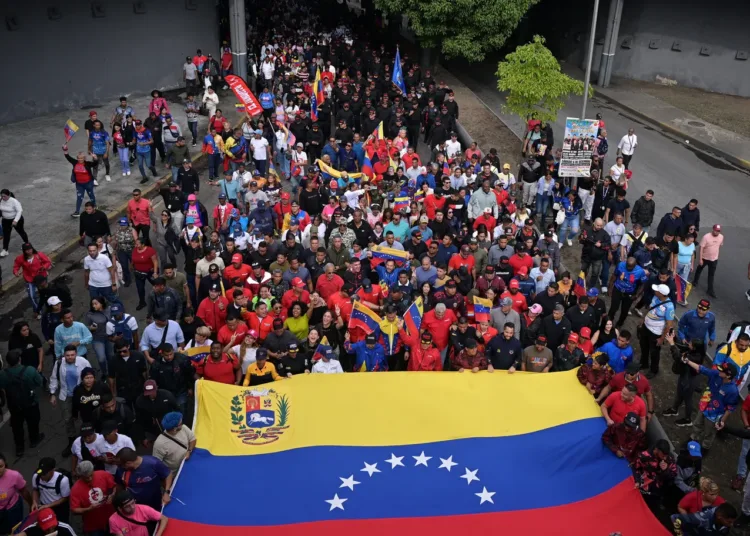 Personas exhiben una gran bandera de Venezuela en una manifestación contra una posible escalada de las acciones estadounidenses, en Caracas, Venezuela, el 25 de noviembre de 2025/Reuters