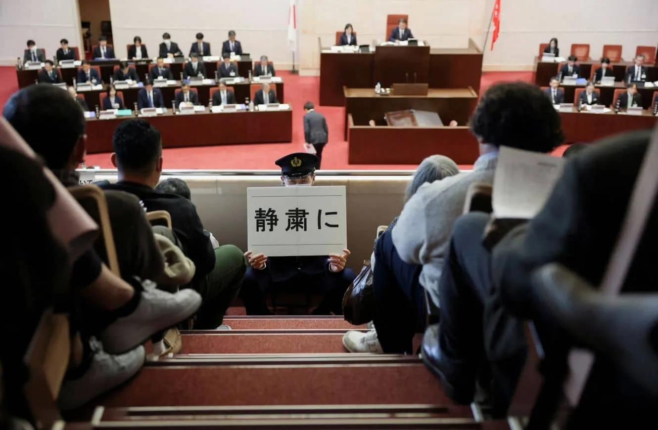 Un oficial de seguridad sostiene un cartel que dice: "Silencio, por favor" cerca de los auditores sentados, mientras los legisladores de la Asamblea de la Prefectura de Niigata participan en una votación de confianza sobre las decisiones del gobernador prefectural relacionadas con el reinicio parcial de la Planta de Energía Nuclear Kashiwazaki Kariwa de la Compañía de Energía Eléctrica de Tokio (TEPCO), una de las plantas nucleares más grandes del mundo y que estuvo entre los reactores cerrados tras un masivo terremoto y tsunami en 2011 que paralizó la planta Fukushima Daiichi de TEPCO, en Niigata, Japón, el 22 de diciembre de 2025. REUTERS/Issei Kato