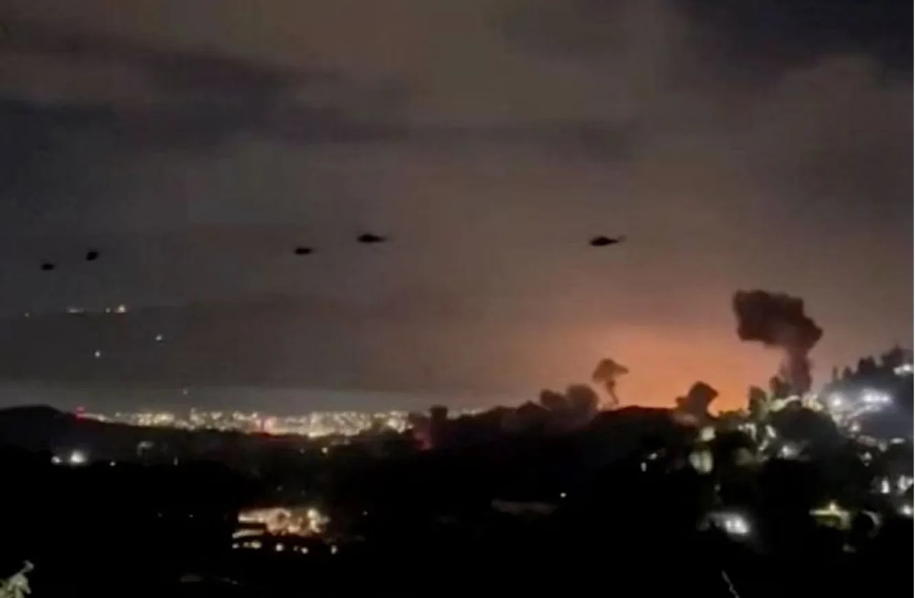 Helicópteros vuelan cerca de columnas de humo que se elevan tras explosiones, en Caracas, Venezuela, el 3 de enero de 2026, en esta captura de pantalla obtenida de un video proporcionado por Reuters. Video proporcionado por Reuters/vía REUTERS