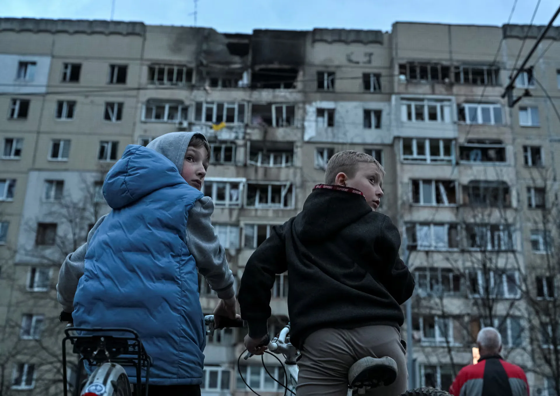 Unos niños en bicicleta se encuentran frente a un bloque de apartamentos alcanzado por un ataque con drones rusos, en el marco de la invasión de Ucrania por parte de Rusia, en el centro de Leópolis (Ucrania). Créditos: REUTERS/Anastasiia Smolienko.