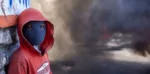 Un manifestante enmascarado se encuentra cerca de una barricada en llamas durante una protesta para exigir la renuncia del presidente haitiano Jovenel Moise en Port-au-Prince, Haití, el domingo / MS