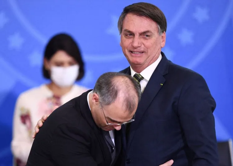 (FILES) In this file photo taken on April 29, 2020 Brazilian President Jair Bolsonaro (R) is embraced by his new Justice Minister Andre Mendonca during the latter's inauguration at Planalto Palace in Brasilia. - Brazilian President Jair Bolsonaro announced on July 12, 2021 that he will appoint his former Justice Minister Andre Mendonca, a Presbyterian pastor, to a vacant position in the Supreme Court, fulfilling his promise to impose a "terribly evangelical" judge in the highest court." (Photo by EVARISTO SA / AFP)