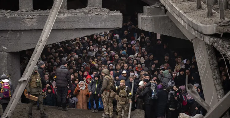 Ukrainians crowd under a destroyed bridge as they try to flee crossing the Irpin river in the outskirts of Kyiv, Ukraine, Saturday, March 5, 2022. (AP Photo/Emilio Morenatti)