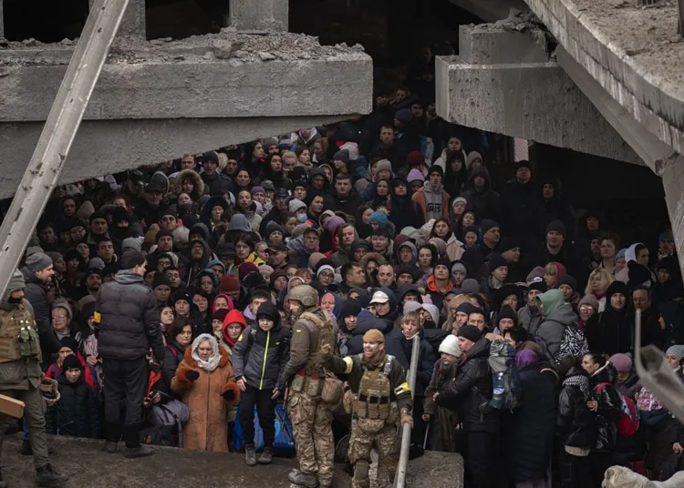 Ukrainians crowd under a destroyed bridge as they try to flee crossing the Irpin river in the outskirts of Kyiv, Ukraine, Saturday, March 5, 2022. (AP Photo/Emilio Morenatti)