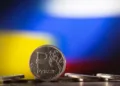 FILE PHOTO: Russian Rouble coins are seen in front of displayed Ukrainian's and Russia's flag colours in this illustration taken, February 24, 2022. REUTERS/Dado Ruvic/Illustration