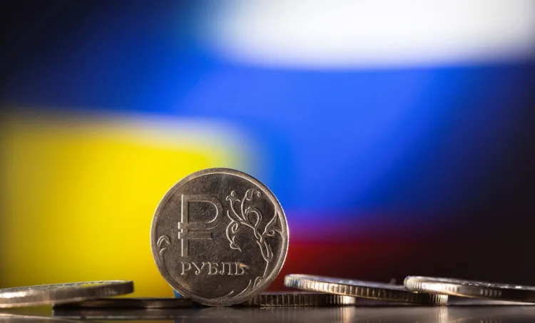 FILE PHOTO: Russian Rouble coins are seen in front of displayed Ukrainian's and Russia's flag colours in this illustration taken, February 24, 2022. REUTERS/Dado Ruvic/Illustration