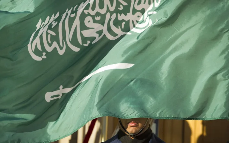 FILE - In this March 22, 2018, file photo, an honor guard member is covered by the flag of Saudi Arabia, in Washington. Saudi Arabia, for years one of the world's most prolific executioners, dramatically reduced the number of people put to death in 2020, following changes halting executions for non-violent drug-related crimes, according to the government’s tally and independent observers. (AP Photo/Cliff Owen, File)