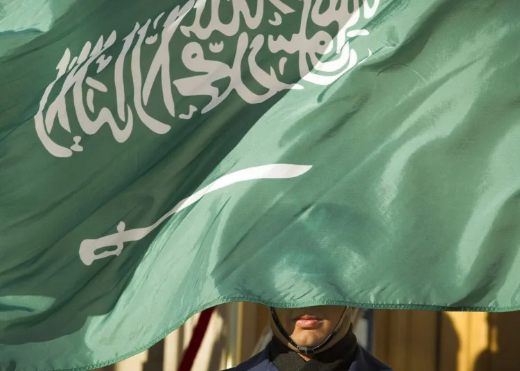 FILE - In this March 22, 2018, file photo, an honor guard member is covered by the flag of Saudi Arabia, in Washington. Saudi Arabia, for years one of the world's most prolific executioners, dramatically reduced the number of people put to death in 2020, following changes halting executions for non-violent drug-related crimes, according to the government’s tally and independent observers. (AP Photo/Cliff Owen, File)