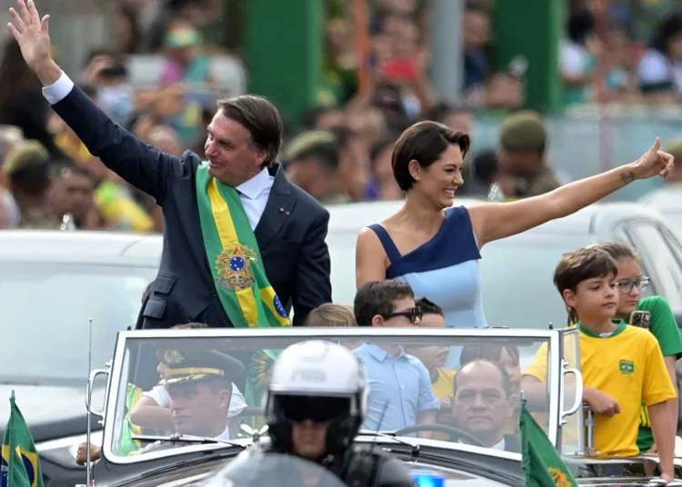 Brazilian President Jair Bolsonaro (L) and First Lady Michelle Bolsonaro wave during a military parade to mark Brazil's 200th anniversary of independence in Brasilia, on September 7, 2022. (Photo by EVARISTO SA / AFP)