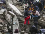 People and emergency teams rescue a person on a stretcher from a collapsed building in Adana, Turkey, Monday, Feb. 6, 2023. A powerful quake has knocked down multiple buildings in southeast Turkey and Syria and many casualties are feared. (IHA agency via AP)