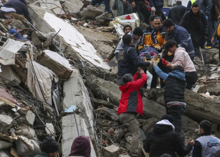 People and emergency teams rescue a person on a stretcher from a collapsed building in Adana, Turkey, Monday, Feb. 6, 2023. A powerful quake has knocked down multiple buildings in southeast Turkey and Syria and many casualties are feared. (IHA agency via AP)