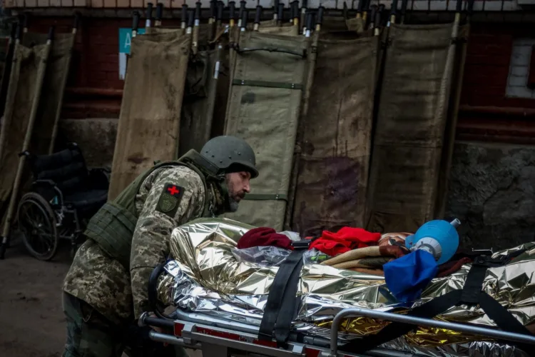 TOPSHOT - This photograph taken on November 28, 2022, shows a volunteer medic from PDMSh (The First Volunteer Mobile Hospital) evacuating a wounded Ukrainian soldier from a stabilizing mobile hospital in the vicinity of Bakhmut, Donetsk region, amid the Russian invasion of Ukraine. - Once known for its vineyards and cavernous salt mines, Bakhmut has now been dubbed "the meat grinder" due to the brutal trench warfare, artillery duels and frontal assaults that have defined the brutal fight for the city for over six months. (Photo by ANATOLII STEPANOV / AFP)