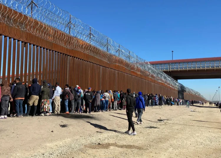 USA2794. EL PASO (TX, EEUU), 21/12/2022.- Migrantes mientras hacen fila para entregarse a la Patrulla Fronteriza estadounidense hoy, en la valla fronteriza de El Paso, Texas, frente a Ciudad Juárez, México. La fuerte presencia militar y policial en la frontera entre México y Estados Unidos, en el límite entre Ciudad Juárez y El Paso, estrechó este miércoles aún más el ya limitado acceso de los migrantes que tratan de pasar. EFE/Octavio Guzmán