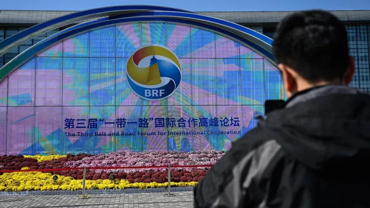 A man takes photos of signage of the Belt and Road Forum in Beijing on October 16, 2023. (Photo by Jade Gao / AFP)
