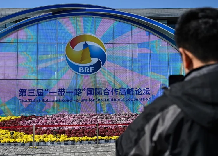 A man takes photos of signage of the Belt and Road Forum in Beijing on October 16, 2023. (Photo by Jade Gao / AFP)