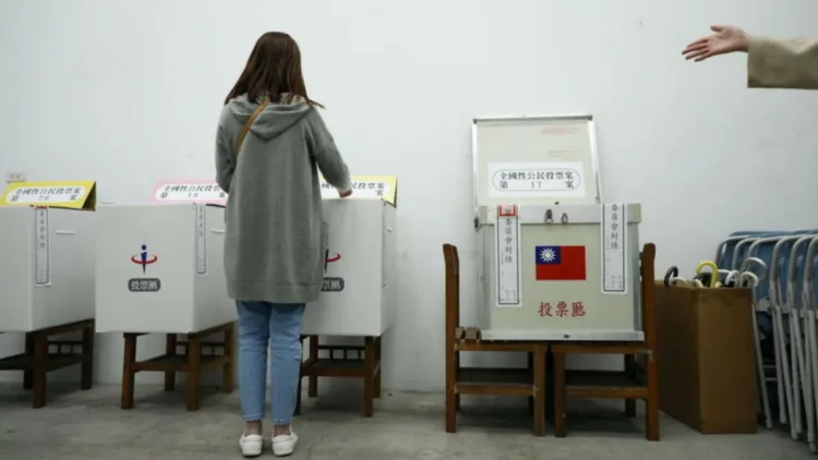 A voter casts her vote into a ballot box at a polling station during a four-question referendum in Taipei, Taiwan December 18, 2021. REUTERS/Annabelle Chih