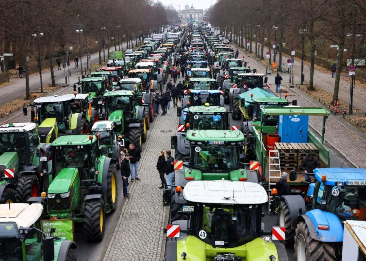 People stand beside tractors, as German farmers take part in a protest against the cut of vehicle tax subsidies, near the Brandenburg Gate in Berlin, Germany, December 18, 2023. REUTERS/Christian Mang