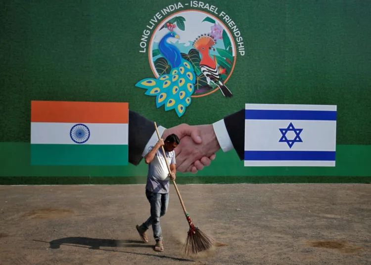 A municipal worker cleans a road in front of a hoarding ahead of the visit of Israeli Prime Minister Benjamin Netanyahu in Ahmedabad, India, January 15, 2018. REUTERS/Amit Dave - RC1ECC0FD2F0