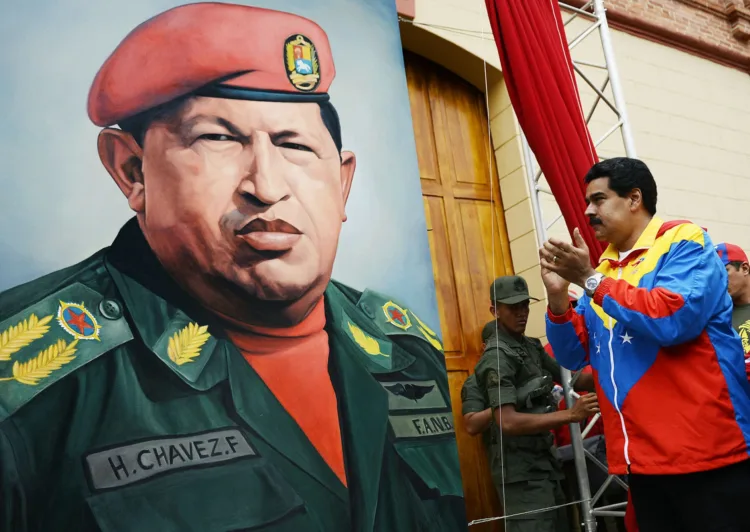 Venezuelan Vice President Nicolas Maduro (R) looks at a portrait of Venezuelan President Hugo Chavez during the conmemoration of the 1992 failed coup led by Chavez, who was an army lieutenant colonel, against then president Carlos Andres Perez, in Caracas, on February 4, 2013. Ailing President Hugo Chavez, who had cancer surgery in December, is doing much better and recovering, Cuban leader Fidel Castro said in remarks published Monday. AFP PHOTO/Juan BARRETO (Photo by Juan BARRETO / AFP) (Photo by JUAN BARRETO/AFP via Getty Images)