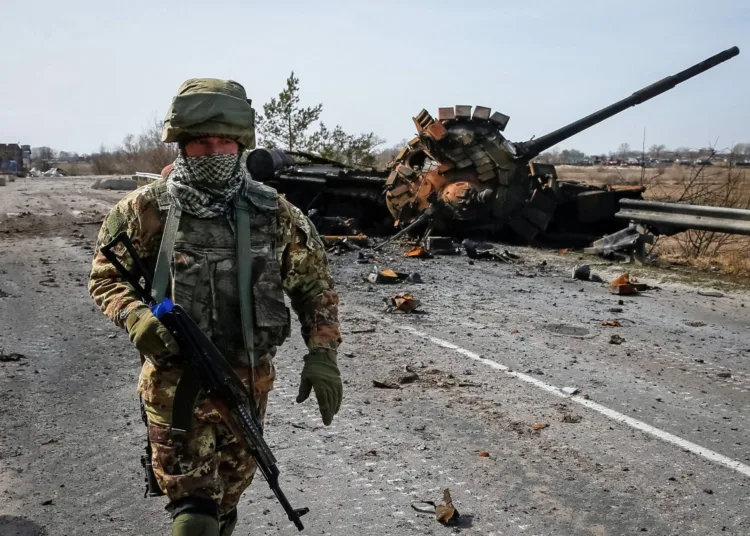 A Ukrainian serviceman walks near the wreck of a Russian tank on the front line in the Kyiv region, Ukraine, on March 28, 2022.