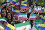 Young women wave national flags of Venezuela and Iran during the arrival of Iranian President Ebrahim Raisi at Miraflores Presidential Palace in Caracas, on June 12, 2023. Iranian President Ebrahim Raisi arrived in Venezuela Monday for the start of a visit to "friendly countries" that also include Cuba and Nicaragua, all under sanctions from a common adversary, the United States. (Photo by Yuri CORTEZ / AFP)