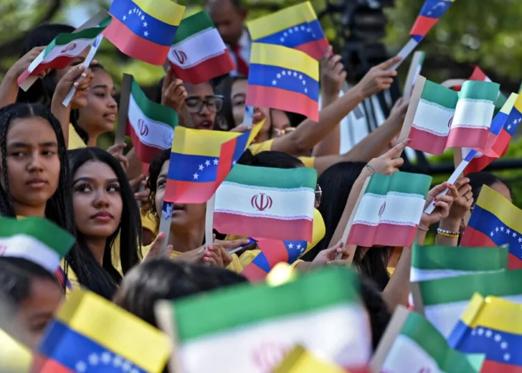 Young women wave national flags of Venezuela and Iran during the arrival of Iranian President Ebrahim Raisi at Miraflores Presidential Palace in Caracas, on June 12, 2023. Iranian President Ebrahim Raisi arrived in Venezuela Monday for the start of a visit to "friendly countries" that also include Cuba and Nicaragua, all under sanctions from a common adversary, the United States. (Photo by Yuri CORTEZ / AFP)