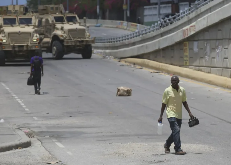 A man walks near armored vehicles of Kenyan police officers part of a UN-backed multinational in Port-au-Prince, Haiti, Wednesday, Sept. 4, 2024. (AP Photo/Odelyn Joseph)