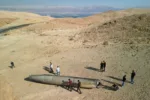 A drone view shows people stand around apparent remains of a ballistic missile lying in the desert, following an attack by Iran on Israel, near the southern city of Arad, Israel October 2, 2024. REUTERS/Amir Cohen