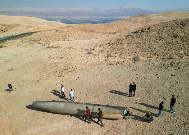 A drone view shows people stand around apparent remains of a ballistic missile lying in the desert, following an attack by Iran on Israel, near the southern city of Arad, Israel October 2, 2024. REUTERS/Amir Cohen