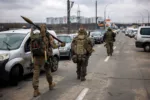 TOPSHOT - Ukrainian servicemen carry rocket-propelled grenades and sniper rifles as they walk towards the city of Irpin, northwest of Kyiv, on March 13, 2022. - Russian forces advance ever closer to the capital from the north, west and northeast. Russian strikes also destroy an airport in the town of Vasylkiv, south of Kyiv. A US journalist was shot dead and another wounded in Irpin, a frontline northwest suburb of Kyiv, medics and witnesses told AFP. (Photo by Dimitar DILKOFF / AFP)