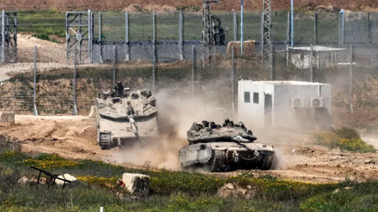 Israeli army Merkava main battle tanks move at a position in southern Israel along the border fence with the northern Gaza Strip on March 18, 2025. Israel on March 18 unleashed its most intense strikes on the Gaza Strip since a January ceasefire, with rescuers reporting 220 people killed, and Hamas accusing Benjamin Netanyahu of deciding to "resume war" after a deadlock on extending the truce.