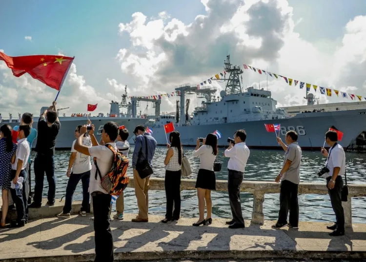 Periodistas cubanos agita banderas de su país y de la República Popular China, mientras varios buques de la Armada china entran en el puerto de La Habana, el 10 de noviembre de 2015. (Foto: Yamil Lage/AFP)
