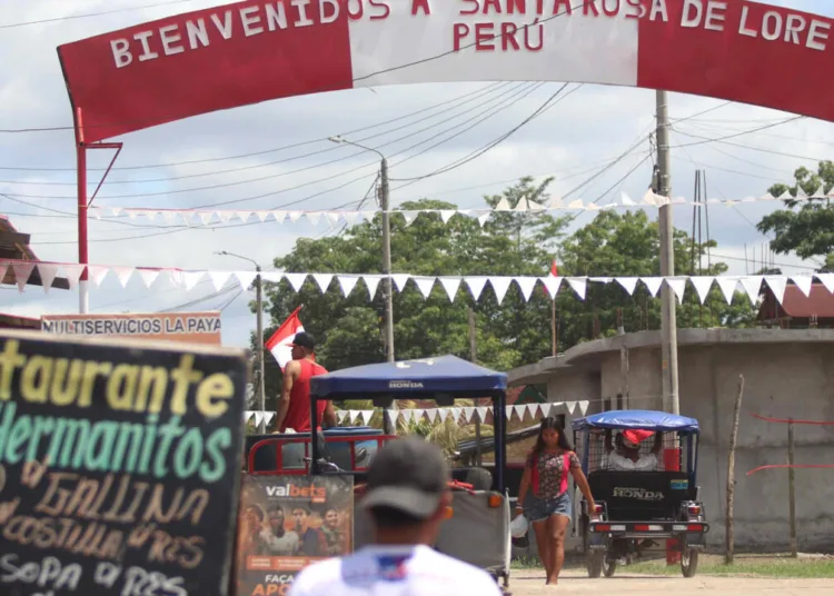 Personas se movilizan en una calle que muestra un letrero fronterizo este miércoles 6 de agosto, en la población de Santa Rosa, una isla en medio del río Amazonas , situada frente a la ciudad colombiana de Leticia, en la triple frontera amazónica con Brasil. © EFE