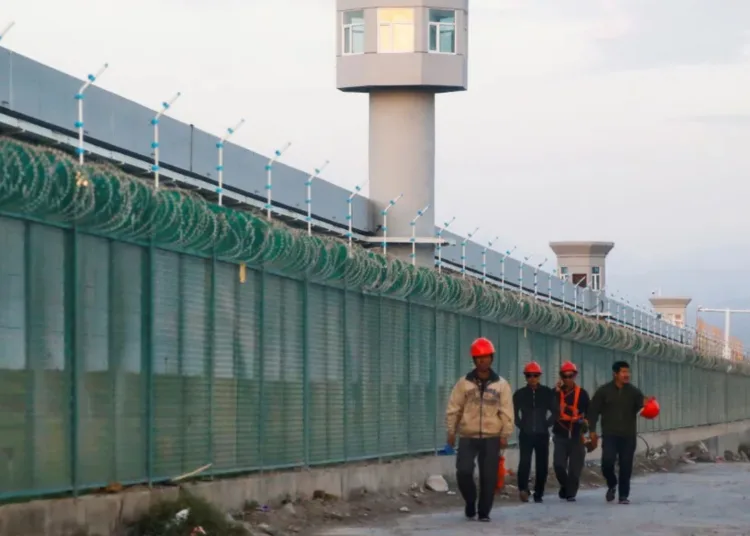 Trabajadores caminan junto a la valla perimetral de lo que oficialmente se conoce como un centro de educación de habilidades vocacionales en Dabancheng, Región Autónoma Uigur de Xinjiang, China, en 2018. (Thomas Peter/Reuters)
