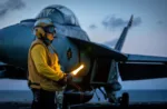 El Suboficial de Primera Clase Sammie Smith, especialista en operaciones de aviación (manejo de aeronaves), asignado al Departamento de Aviación a bordo del portaaviones más grande del mundo, el USS Gerald R. Ford (CVN 78), da señales a un F/A-18E Super Hornet del Ala Aérea Embarcada 8, adscrito al Escuadrón de Caza de Ataque 31, el 10 de octubre de 2025. El Gerald R. Ford, un portaaviones de primera clase y buque insignia desplegado del Grupo de Ataque de Portaaviones 12, se encuentra en una misión programada en el área de operaciones de la 6ª Flota de EE. UU. para apoyar la efectividad en combate, la letalidad y la preparación de las Fuerzas Navales de EE. UU. en Europa y África, y para defender los intereses de EE. UU., aliados y socios en la región.