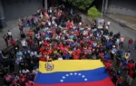 Personas exhiben una gran bandera de Venezuela en una manifestación contra una posible escalada de las acciones estadounidenses, en Caracas, Venezuela, el 25 de noviembre de 2025/Reuters