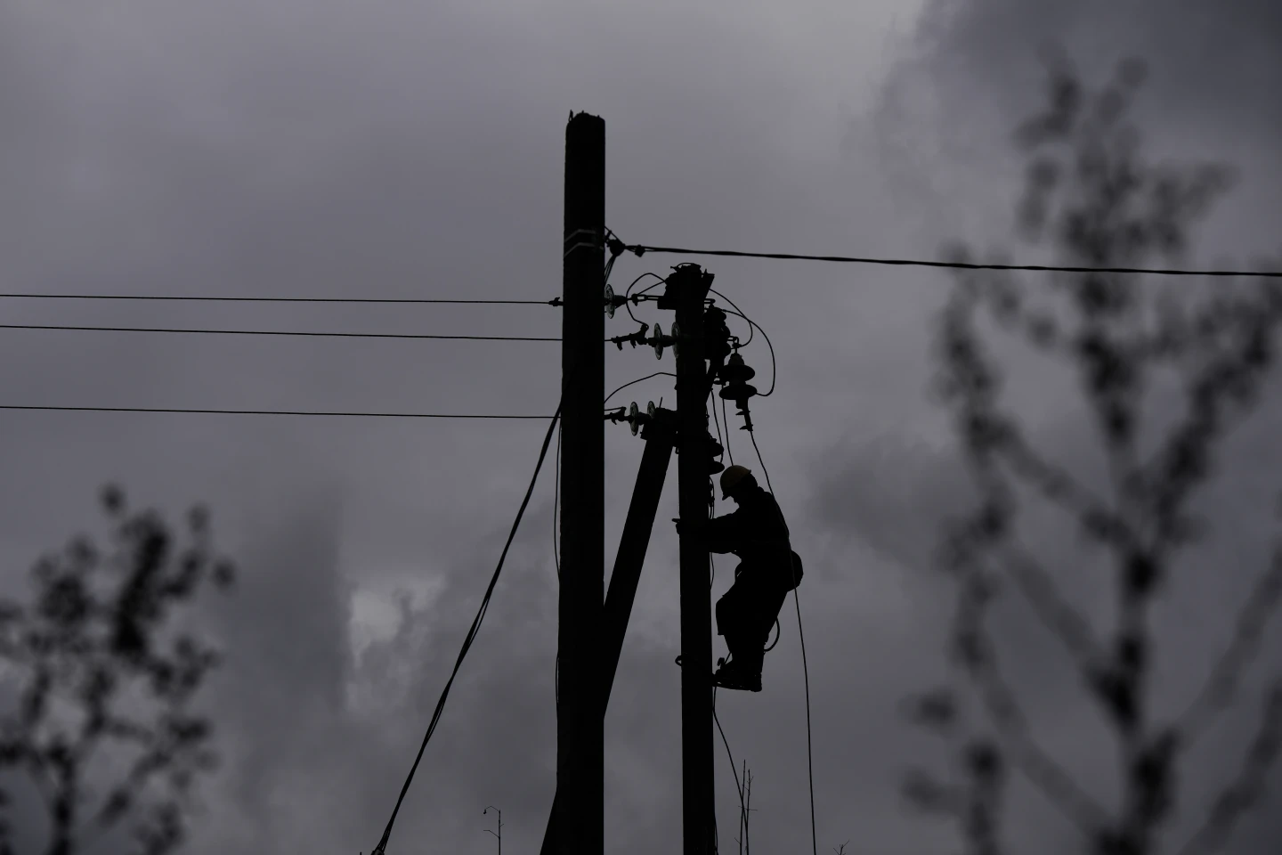 A worker climbs a utility pole while repairing power lines damaged in a Russian attack, Thursday, Oct. 16, 2025, in Shostka, Ukraine. (AP Photo/Julia Demaree Nikhinson)