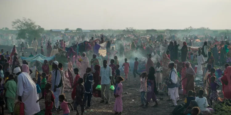 Las personas recién llegadas que huyen del conflicto en Sudán se reúnen en el paso fronterizo de Joda, en Sudán del Sur, a la espera de ser transportadas al centro de tránsito de Renk. Crédito: ACNUR/Ala Kheir