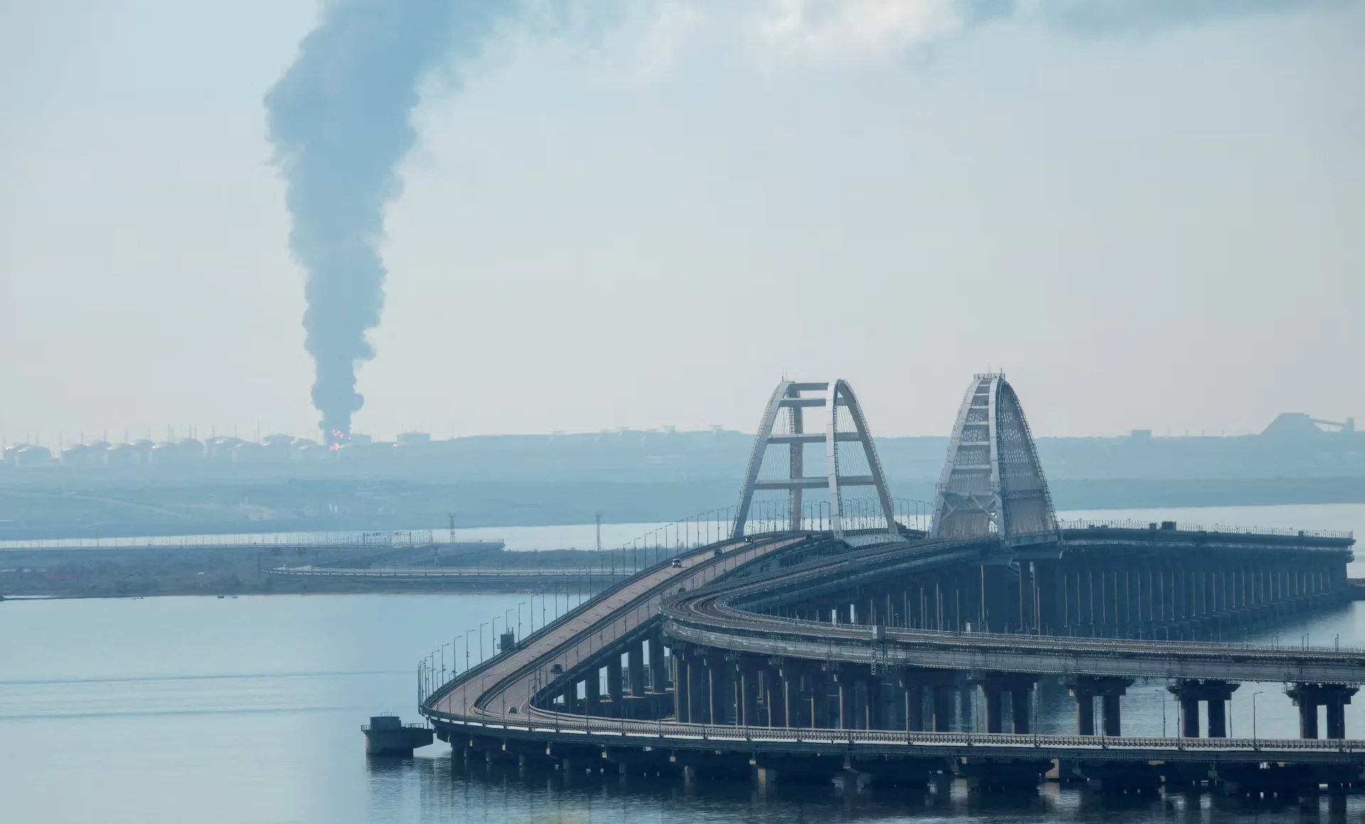 Una densa columna de humo se eleva desde un depósito de combustible ruso en llamas cerca del Puente de Crimea, una ruta clave que conecta Rusia con Crimea y que Moscú utiliza para transportar tropas y equipo al frente en Ucrania. Créditos: REUTERS/Stringer.