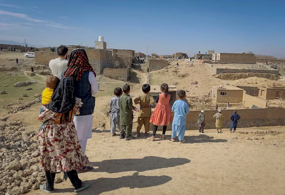 Unos niños junto a una casa dañada en lo que, según los talibanes, fue un ataque aéreo pakistaní en las afueras de Kabul, Afganistán, el 13 de marzo de 2026. Fotografía tomada con un teléfono móvil. Créditos: REUTERS/Sayed Hassib