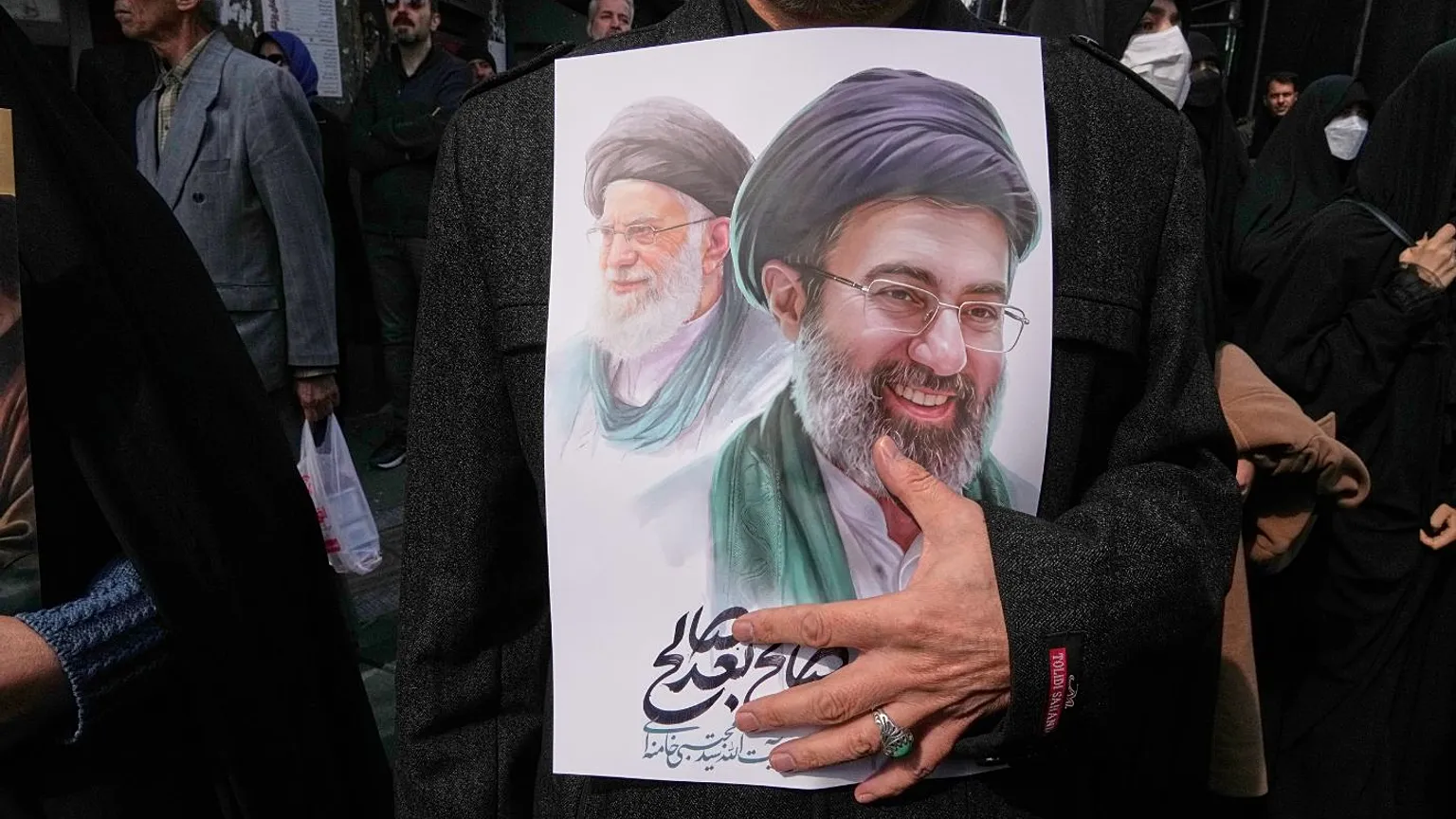 Mujer sostiene una imagen del ex líder supremo Alí Jamenei y el actual Mojtaba Jamenei en una manifestación en Teherán posterior a su nombramiento. Crédito: AP Photo