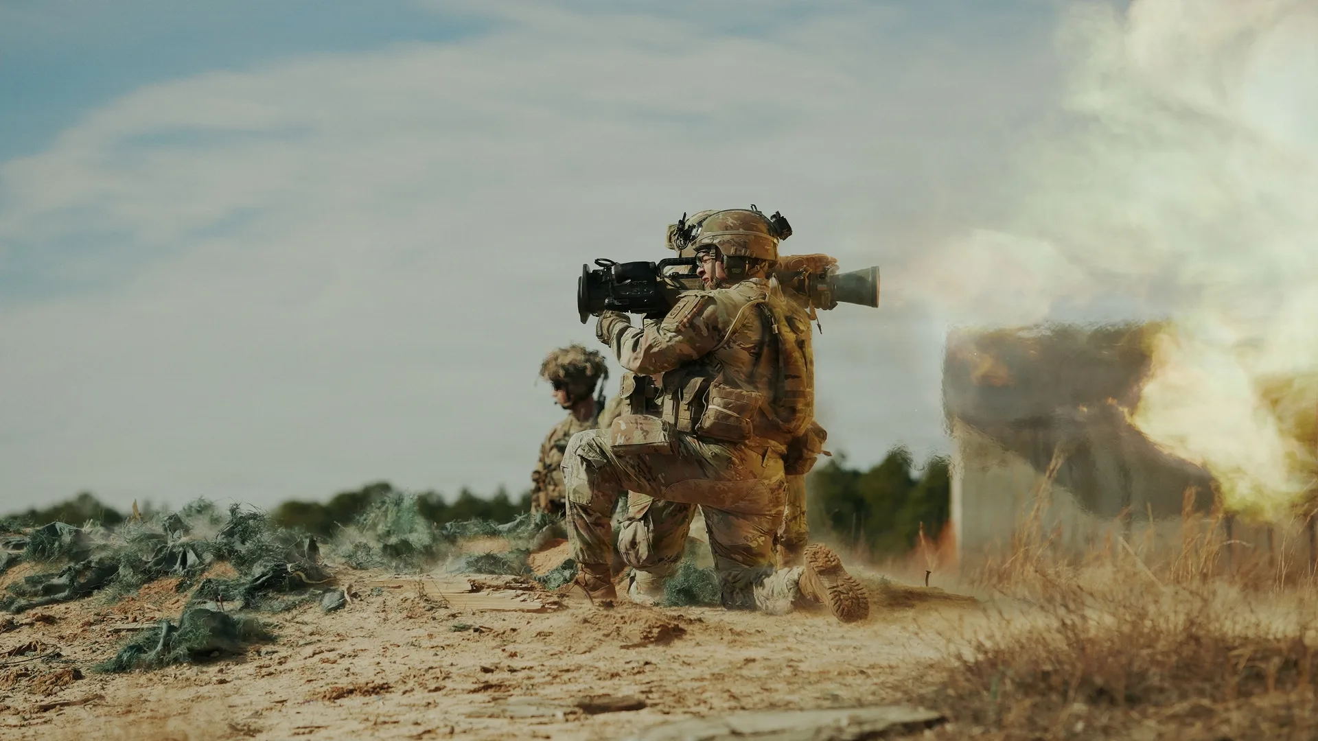 Paracaidistas estadounidenses entrenando en un campo de tiro con ametralladoras pesadas y lanzacohetes, disparando con precisión en posiciones prono y arrodilladas entre casquillos y explosiones. Créditos: Departamento de Guerra EE.UU.