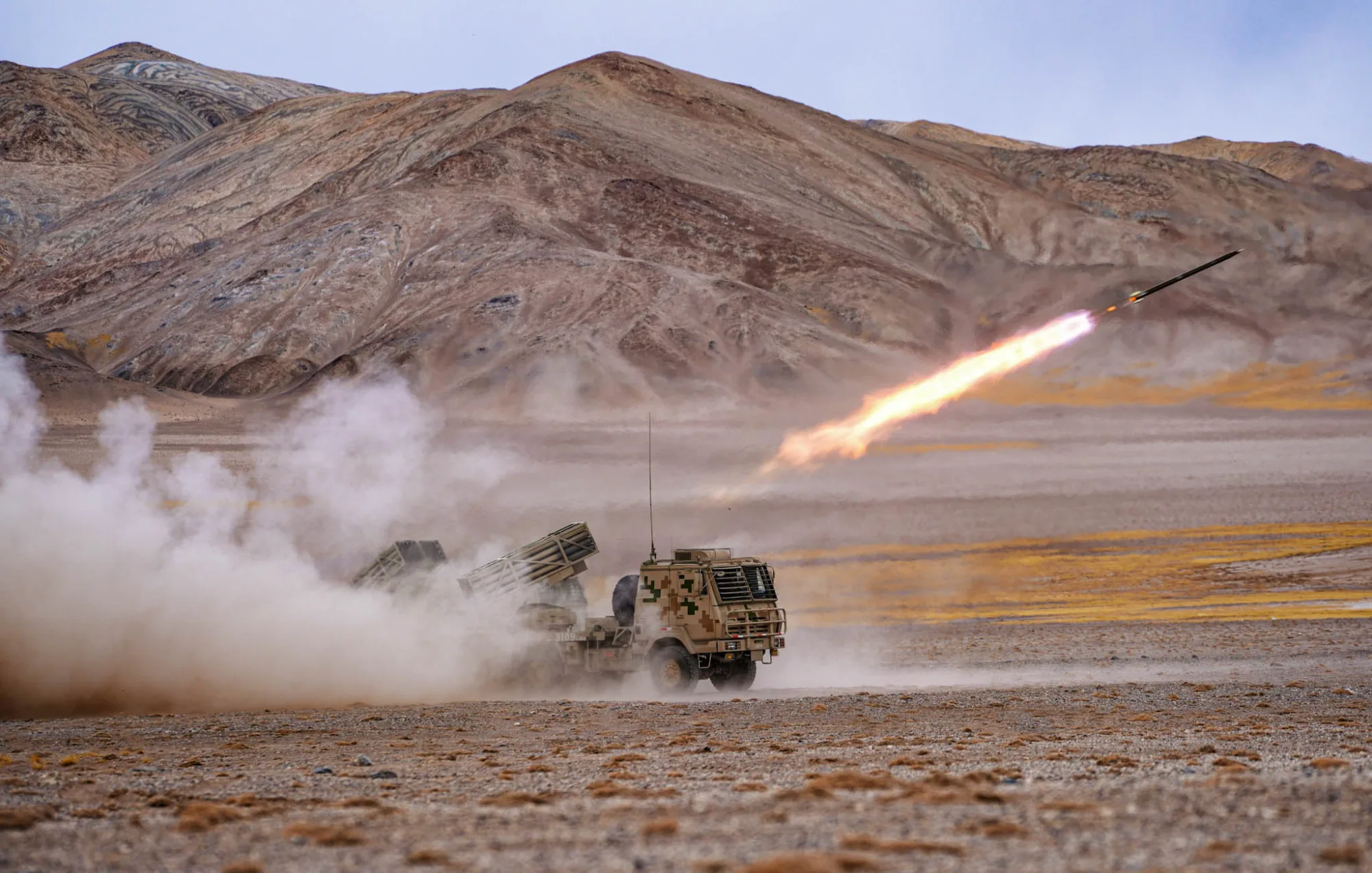 Obuses PCL-181 montados en vehículos y sistemas de lanzamiento de cohetes múltiples pertenecientes a un regimiento del ejército bajo el Mando Militar de Xinjiang del EPL chino, abriendo fuego durante un ejercicio de entrenamiento de tiro con munición real en el interior de la cordillera del Karakórum. Créditos: Cuenta oficial de prensa de las fuerzas armadas de China.