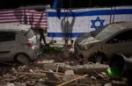 Las autoridades israelíes cuelgan banderas de Israel y Estados Unidos en el lugar impactado por un misil iraní que mató a dos personas, en Ramat Gan, Israel, el miércoles 18 de marzo de 2026. Oded Balilty / AP