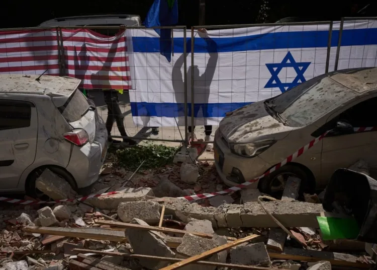 Las autoridades israelíes cuelgan banderas de Israel y Estados Unidos en el lugar impactado por un misil iraní que mató a dos personas, en Ramat Gan, Israel, el miércoles 18 de marzo de 2026. Oded Balilty / AP