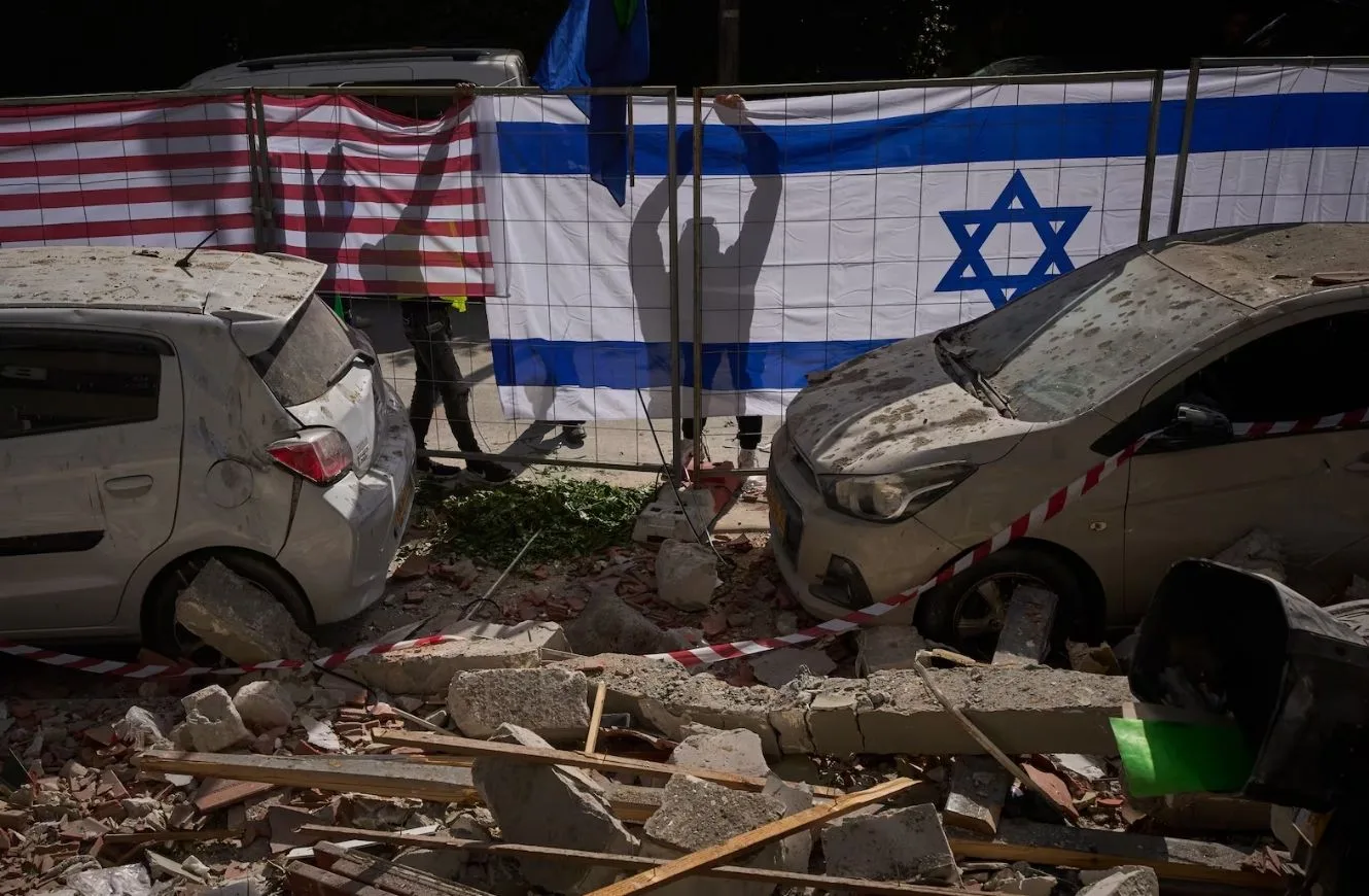Las autoridades israelíes cuelgan banderas de Israel y Estados Unidos en el lugar impactado por un misil iraní que mató a dos personas, en Ramat Gan, Israel, el miércoles 18 de marzo de 2026. Oded Balilty / AP
